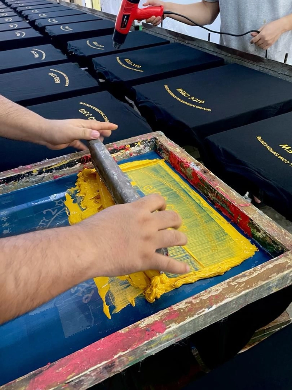 Silkscreen colour layer being printed across a batch of company shirts